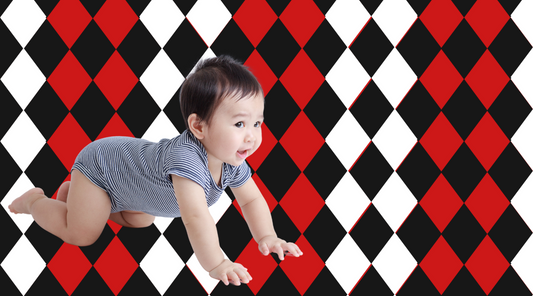 Baby developing visual tracking skills with high-contrast black, white, and red design behind them—illustrating how movement and bold patterns support infant eye development, from Baby Geometrics