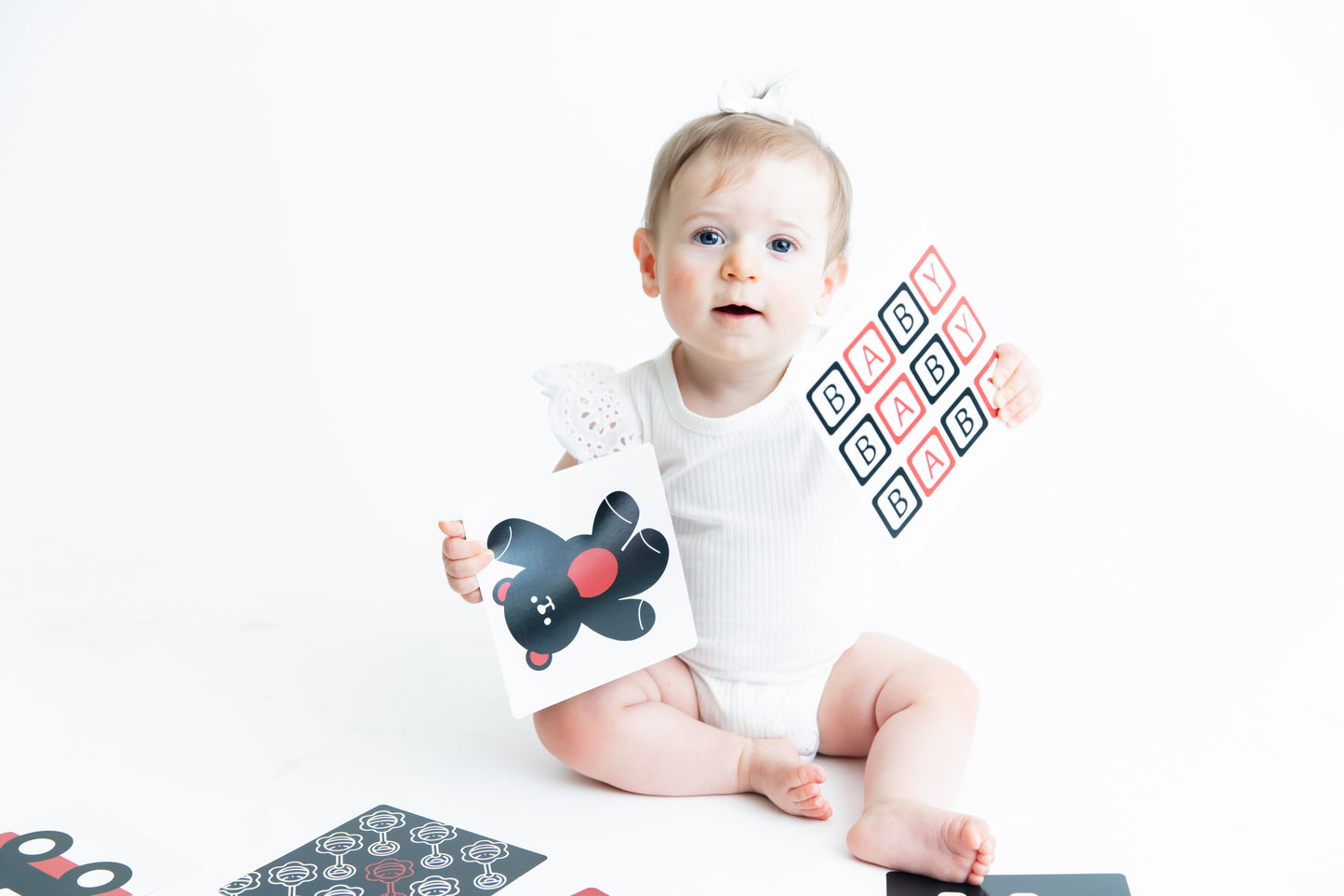 Our little Baby Geometrics model is showing off her baby vision flashcards, displaying high contrast patterns in red, black and white.
