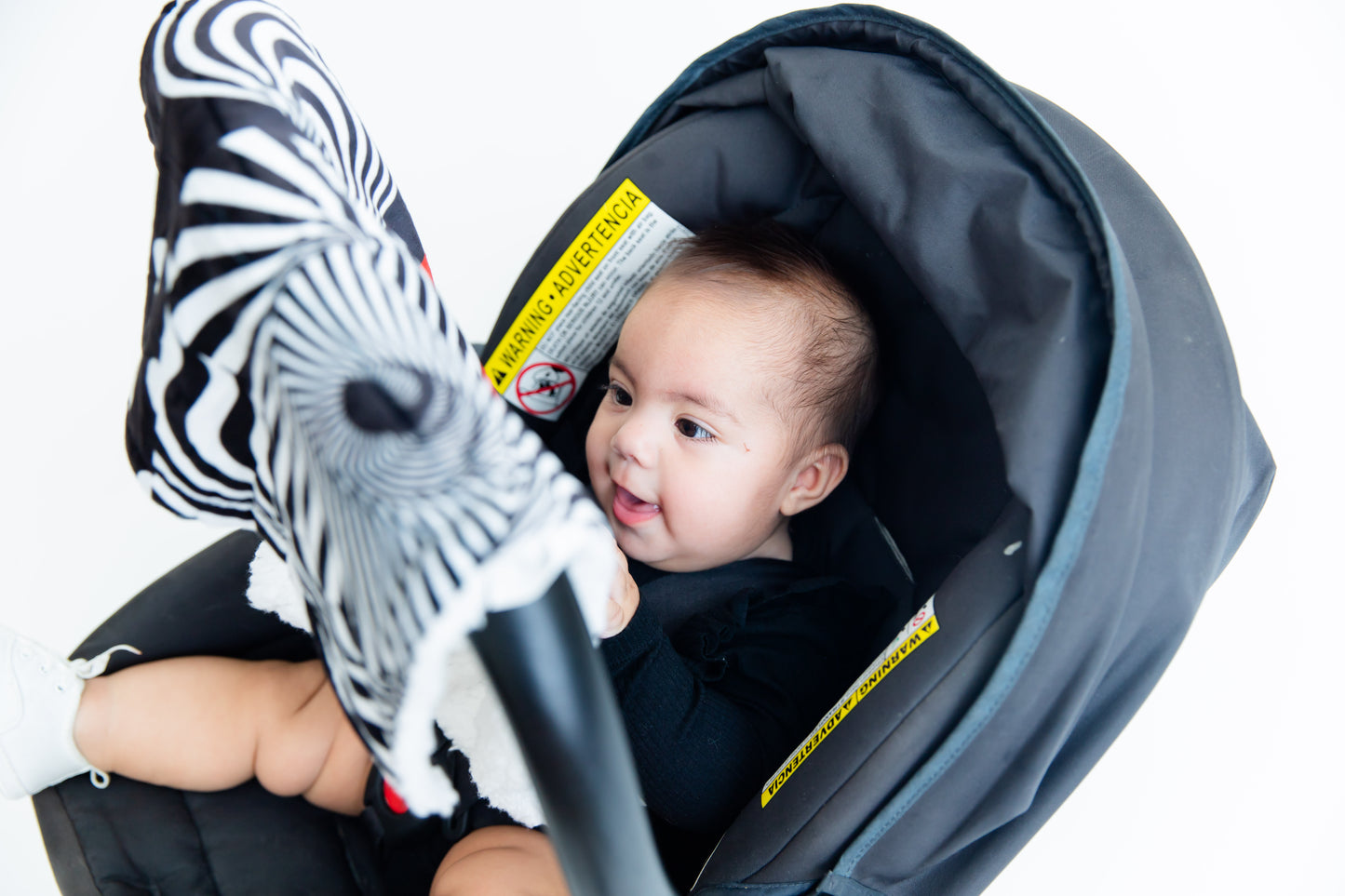 Baby smiling with joy while engaging with the Baby Geometrics high-contrast blanket, featuring bold patterns designed to stimulate early visual development and spark curiosity.