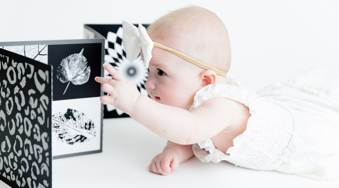Baby reaching for black and white high contrast baby vision board by Baby Geometrics. Babies prefer black and white contrast over pastels and Baby Geometrics designs and creates products that engage little ones. 