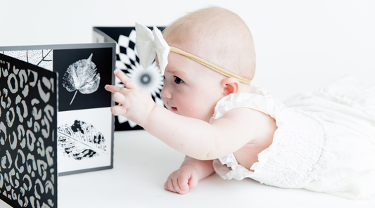 Baby reaching for black and white high contrast baby vision board by Baby Geometrics. Babies prefer black and white contrast over pastels and Baby Geometrics designs and creates products that engage little ones. 