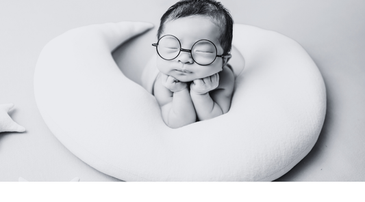 High Contrast Designs Improve Baby's Long Term version, this little baby is propped up on a bobby wearing glasses, order high contrast products to support vision at Baby Geometrics