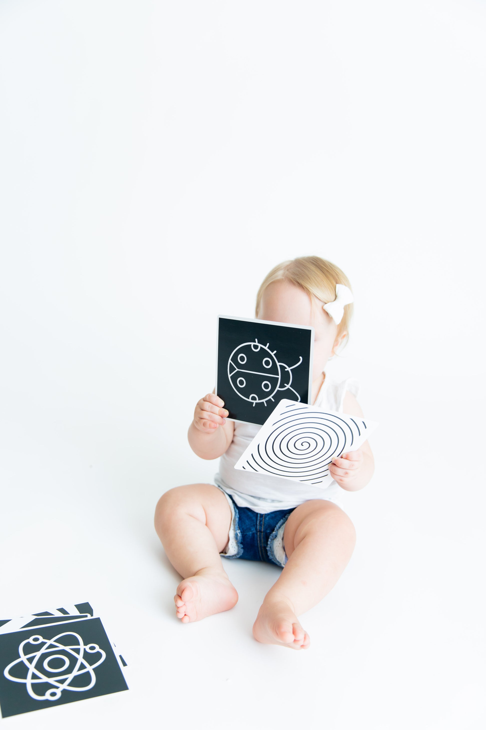 Baby holding a Baby Geometrics flashcard, intently engaging with the high-contrast black-and-white design to stimulate visual and cognitive development.