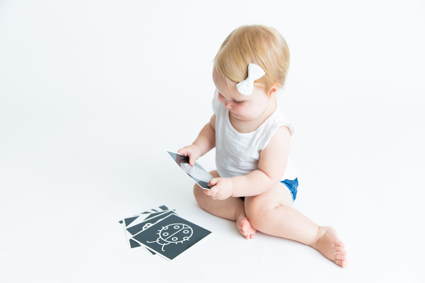 Baby holding a Baby Geometrics flashcard, intently engaging with the high-contrast black-and-white design to stimulate visual and cognitive development.